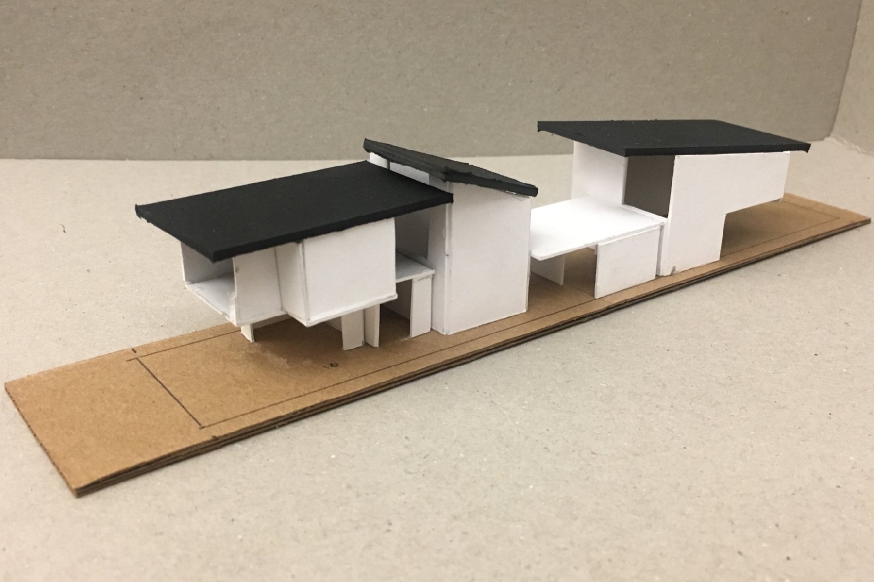 Hand-built massing model of three connected volumes with dark roofs