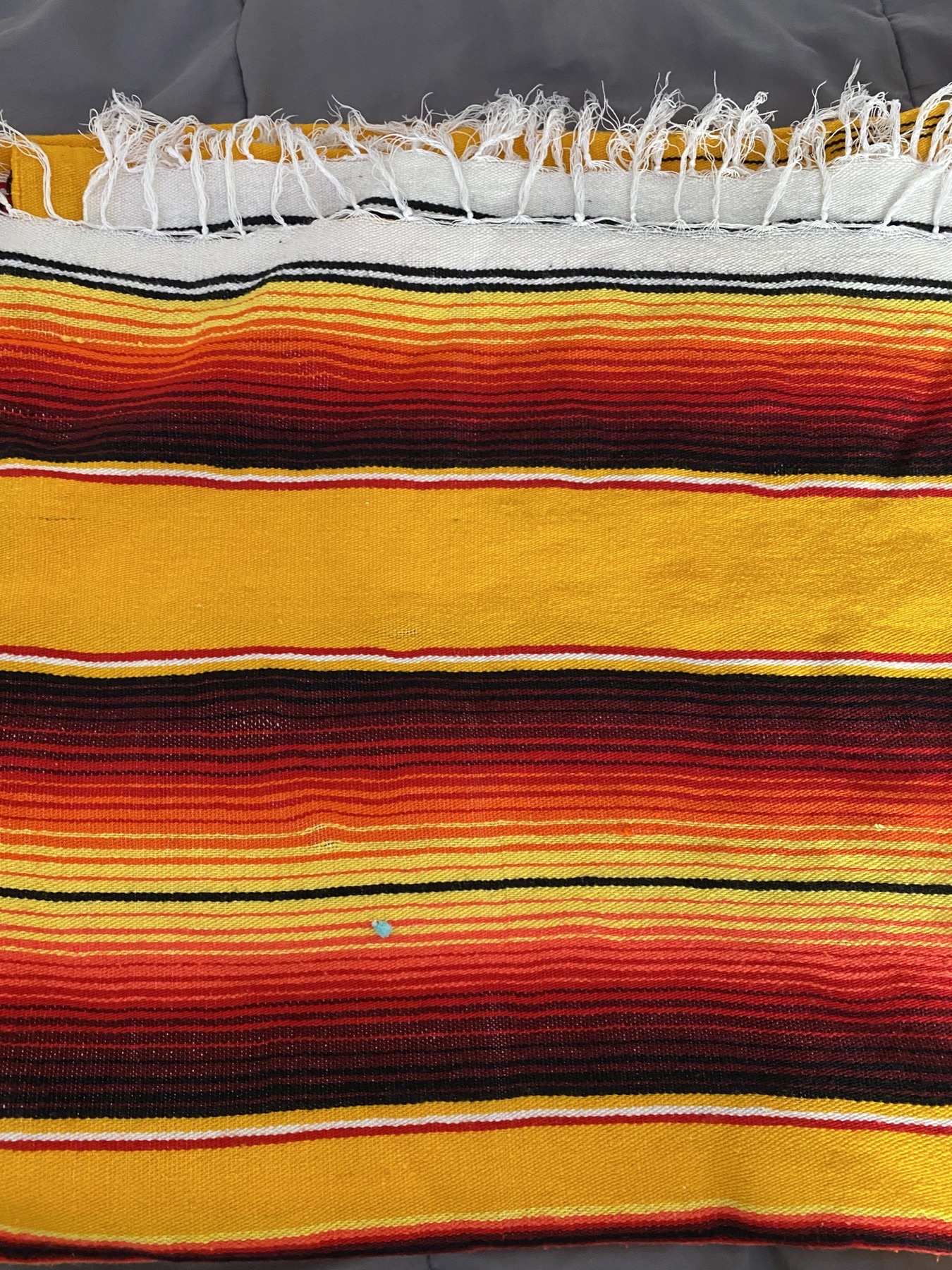 Sarape-style blanket with vibrant yellow, orange, and red stripes and white fringe